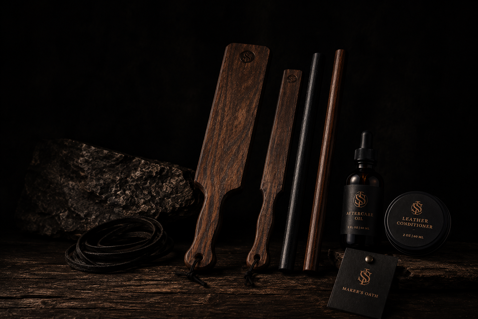 The Sub Space Boutique wooden discipline tools arranged on a matte black and copper display