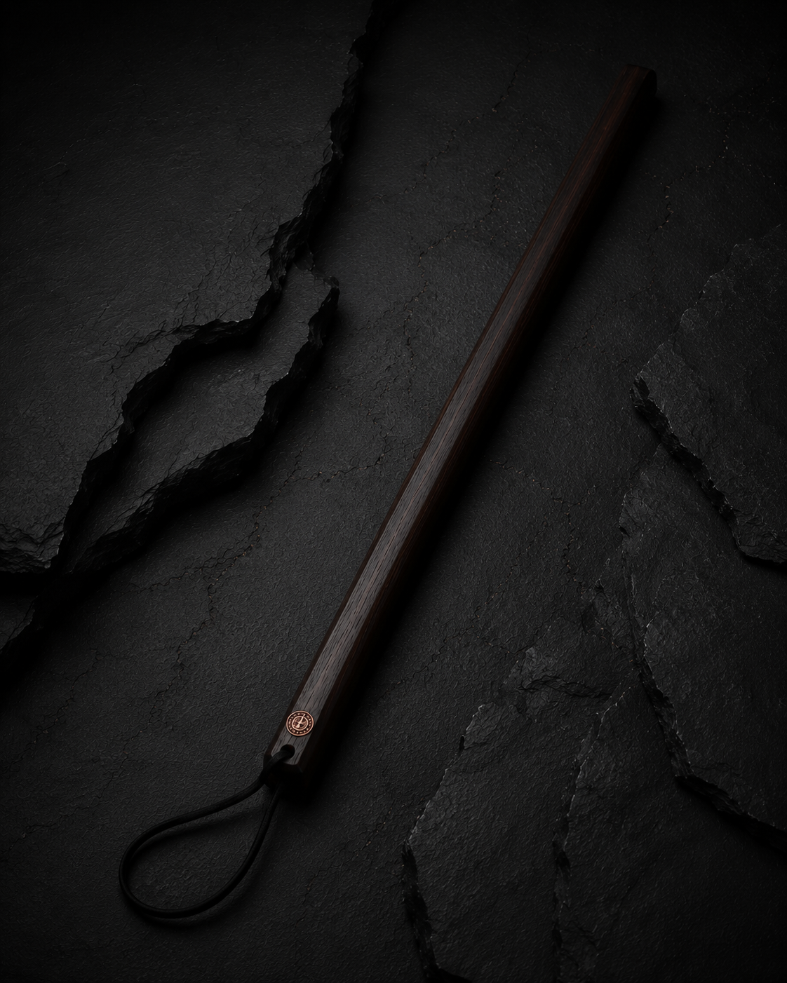 Straight wooden consequence cane on a blackened wood surface