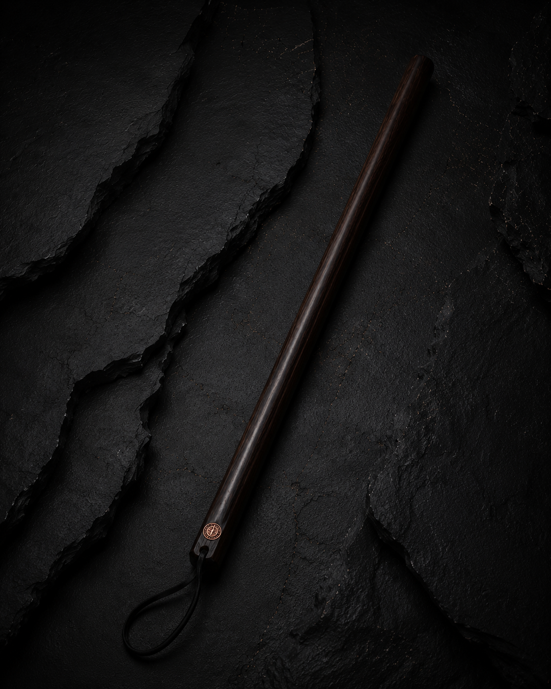 Straight wooden course correction cane on a blackened wood surface
