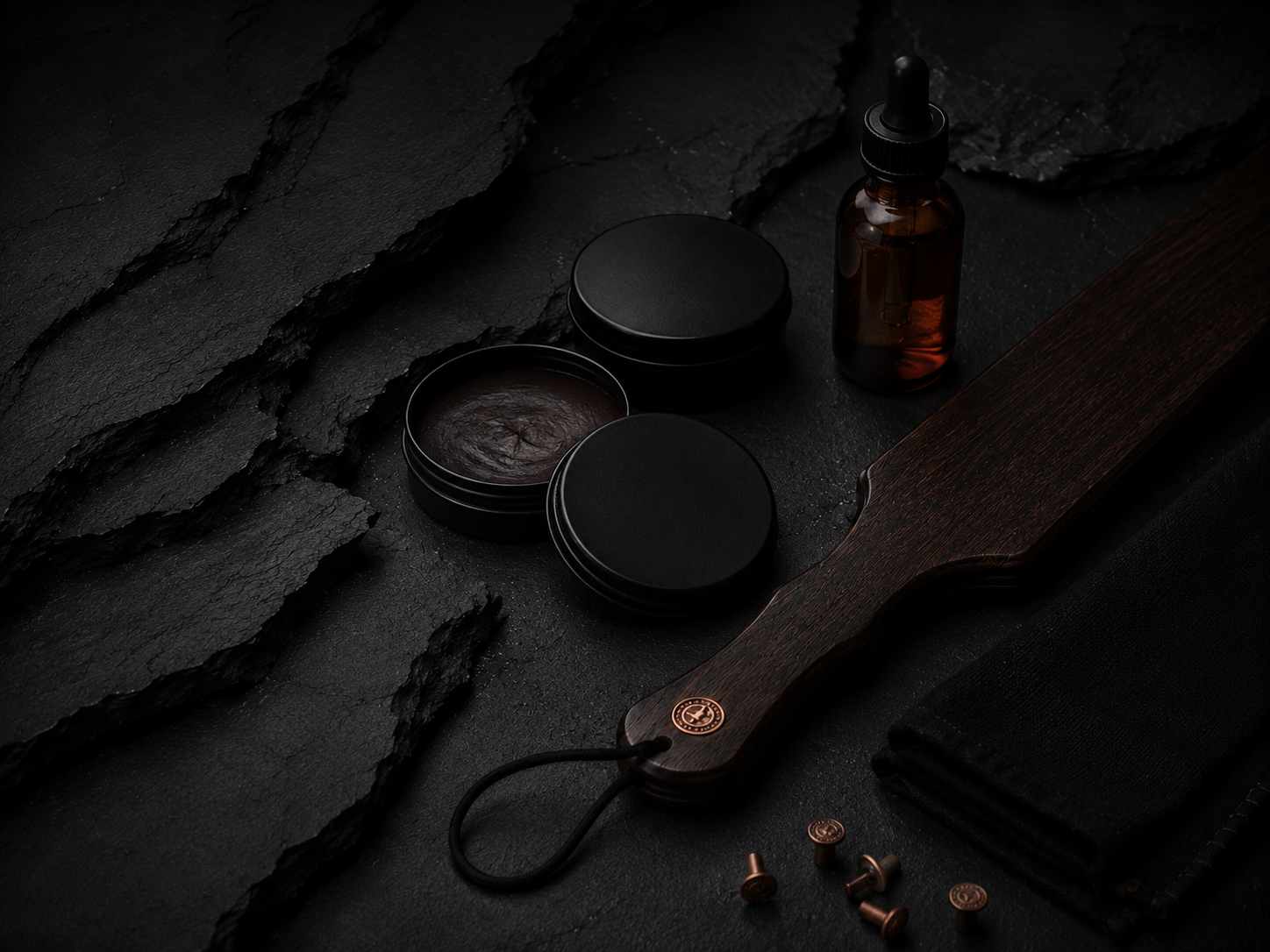 Matte black finish oils and care provisions arranged on a dark bench