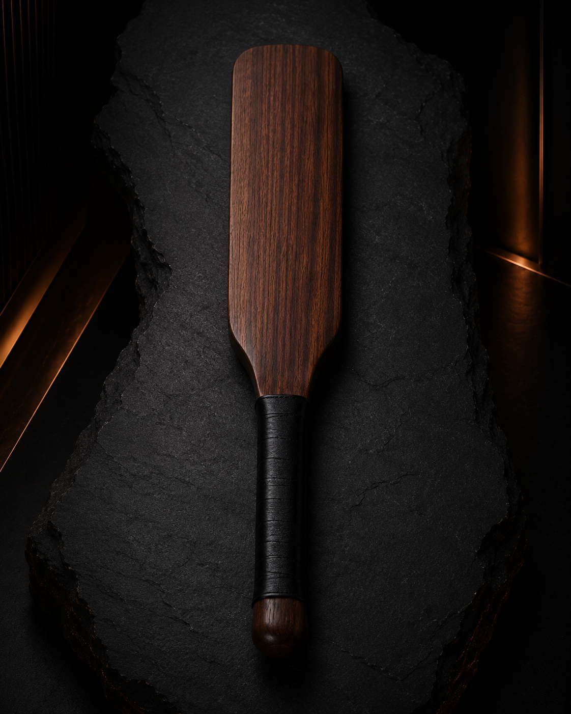 Full wooden discipline paddle on a dark archival surface