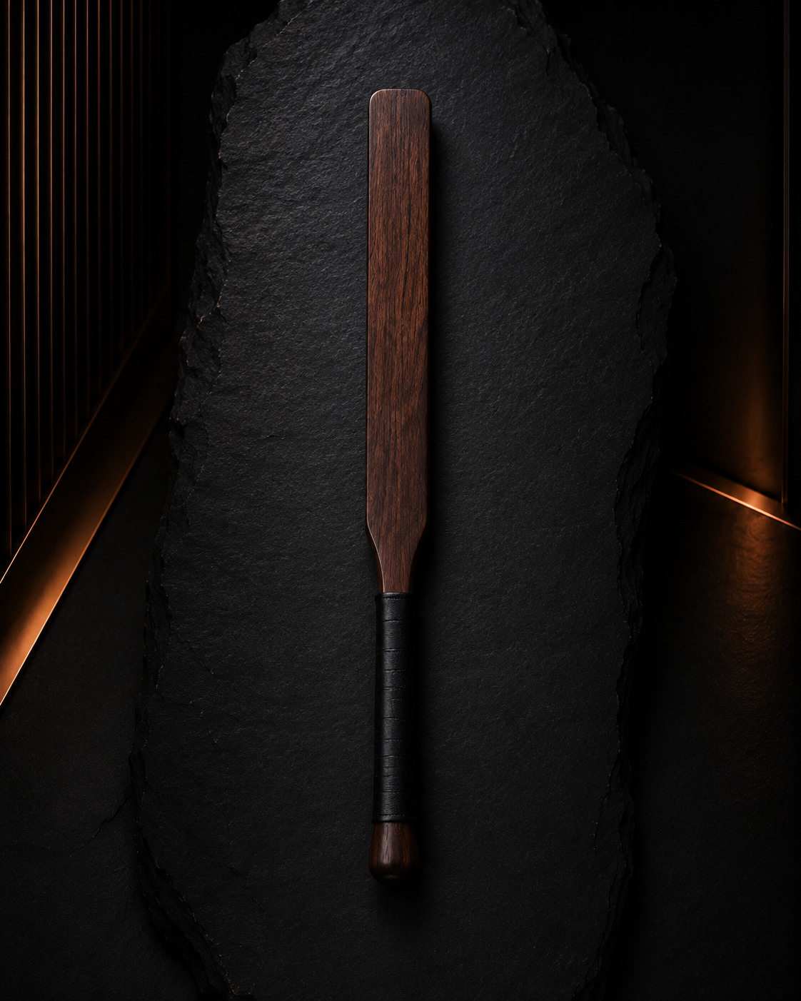 Slim wooden discipline paddle on a dark archival surface